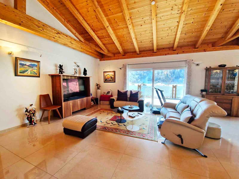 large living room with beige couches, ottoman, coffee table, TV stand, fireplace, dining table, chairs, windows, carpet, wooden ceiling