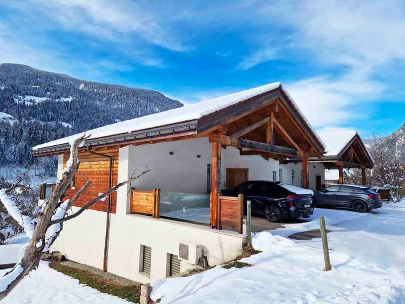 Modern Alpine style house, white and brown exterior, raised ground floor, covered parking for two cars
