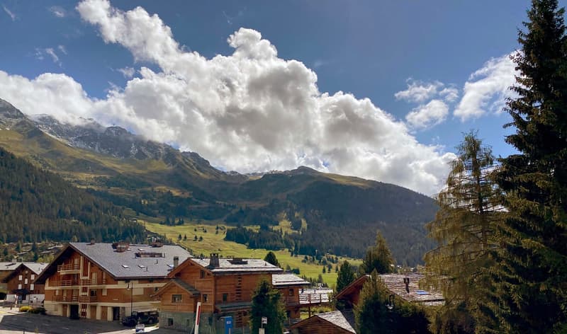 Wooden chalets, mountainous terrain, cloudy sky, greenery