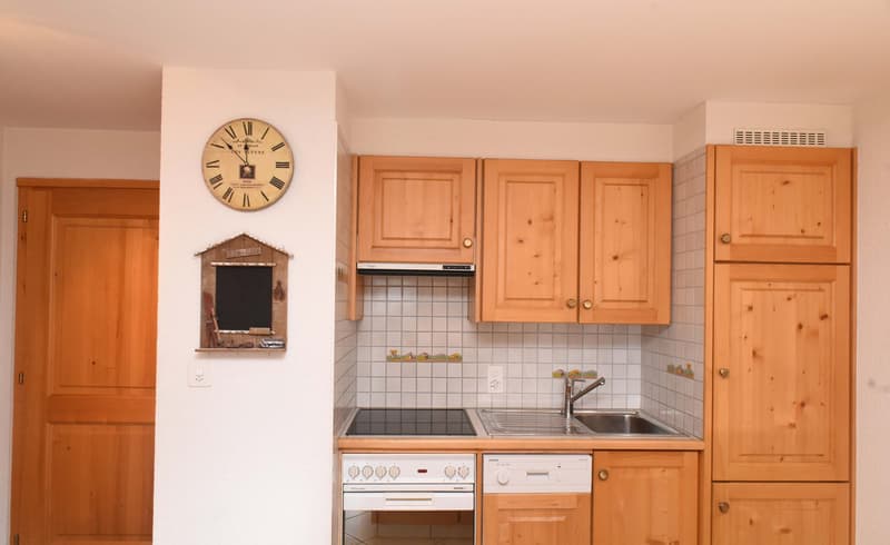 Small kitchen, gas stove, sink, dishwasher, wooden cabinets, tiled walls, wall clock, power outlets