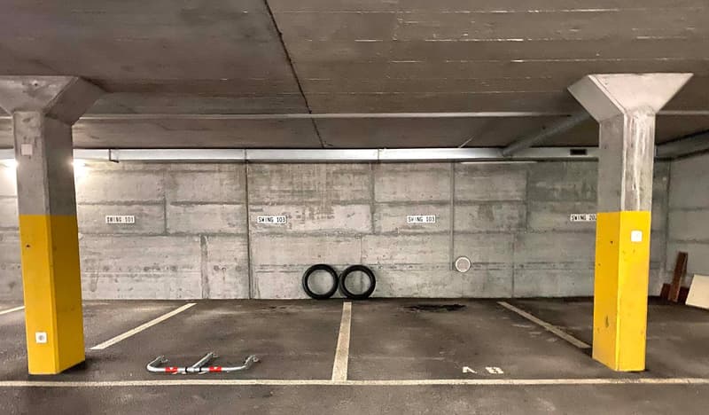 Empty parking spot with walls, poles, and designated parking number signs.