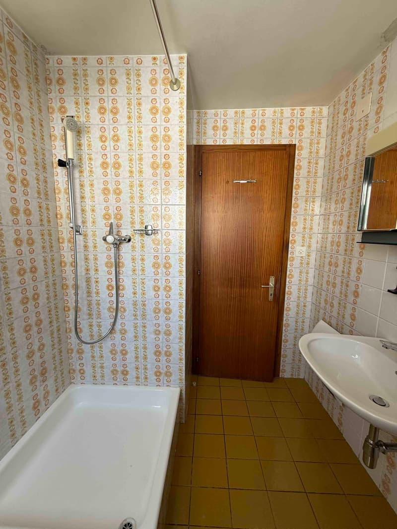 shower, bathtub, sink, toilet, wooden door, tiled walls, floral wallpaper