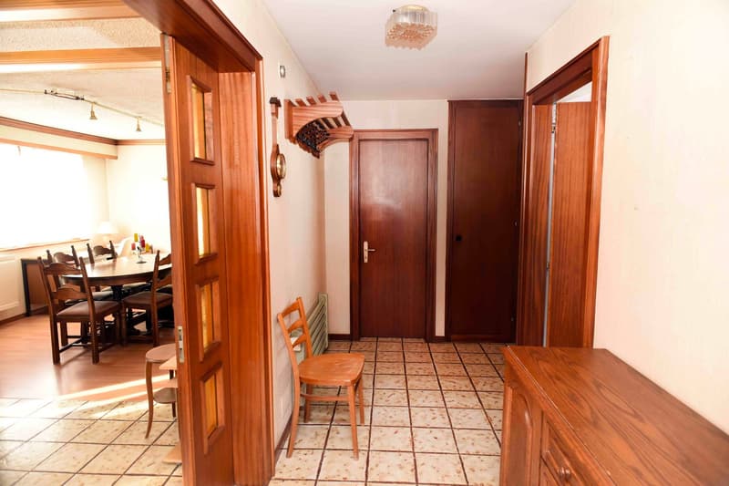 tiled floor, wooden doors, wooden chair, radiator, hallway leading to dining area