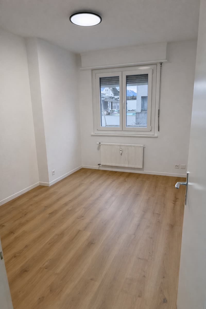 Wooden floors, white walls, white radiators, open window with white blinds, modern ceiling light