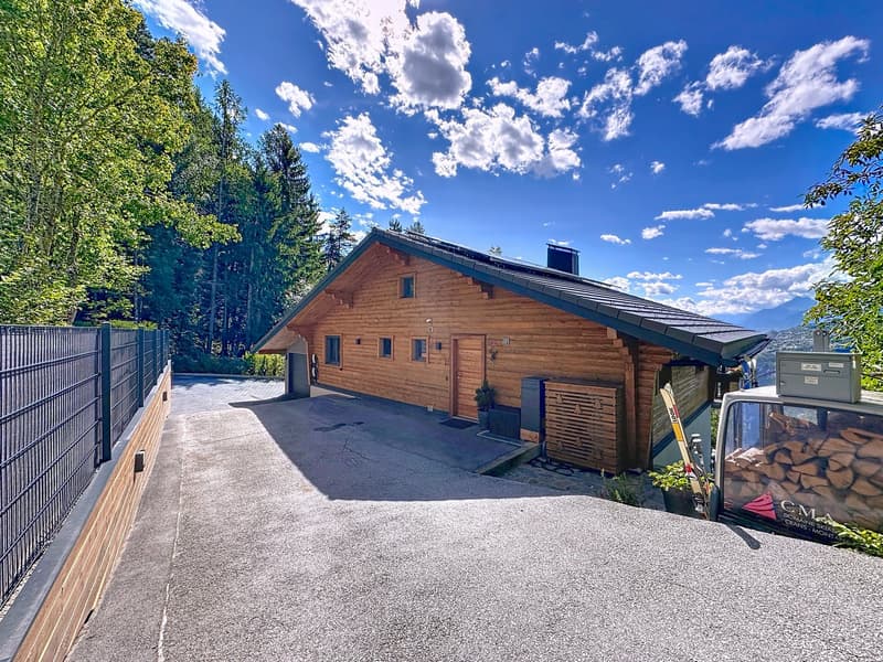 Wooden house, black shingles, solar panels, garage, garden, mountain view