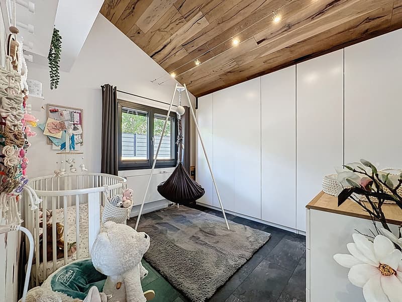 Contemporary nursery with wooden ceiling, white walls, crib, toys, rug, and white cabinet
