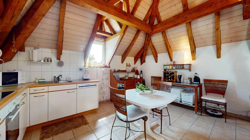 small attic room with wooden beams, kitchen, dining table, small sink, dishwasher, and microwave
