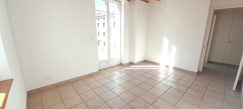 Empty room with white walls, tile flooring, sliding doors, power outlets