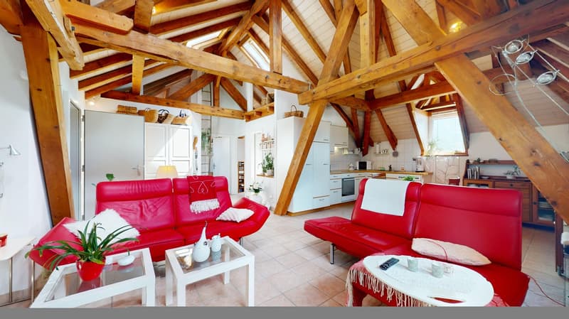 open plan living area with exposed wooden beams, red couches, coffee tables, kitchen