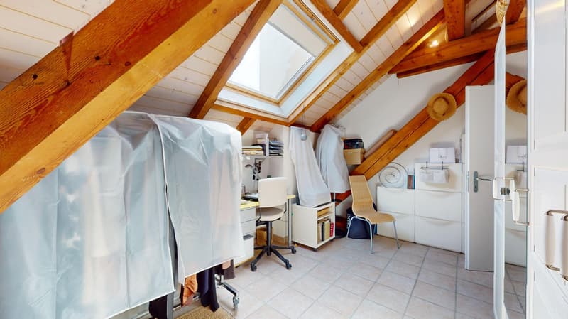 Slanted wooden ceiling, tiled floor, desk, chair, storage cabinet, skylight