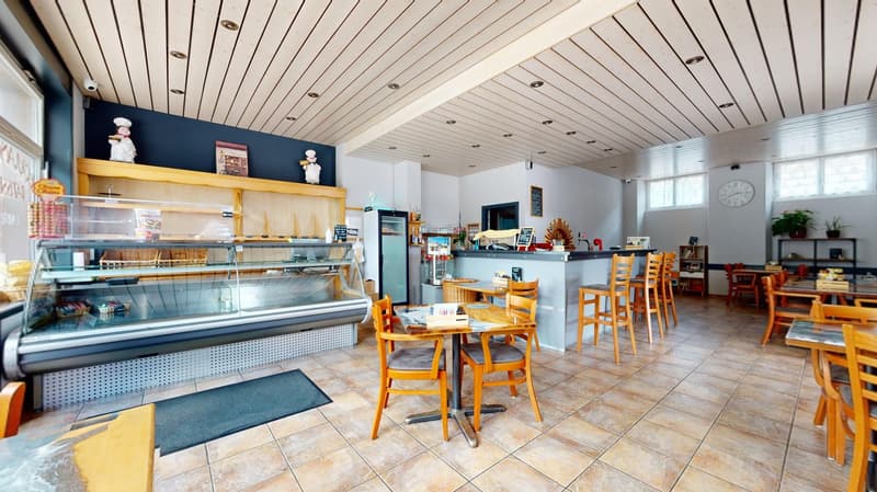 wooden counter, tables and chairs, display case with bakery products, wall decoration, open refrigerator