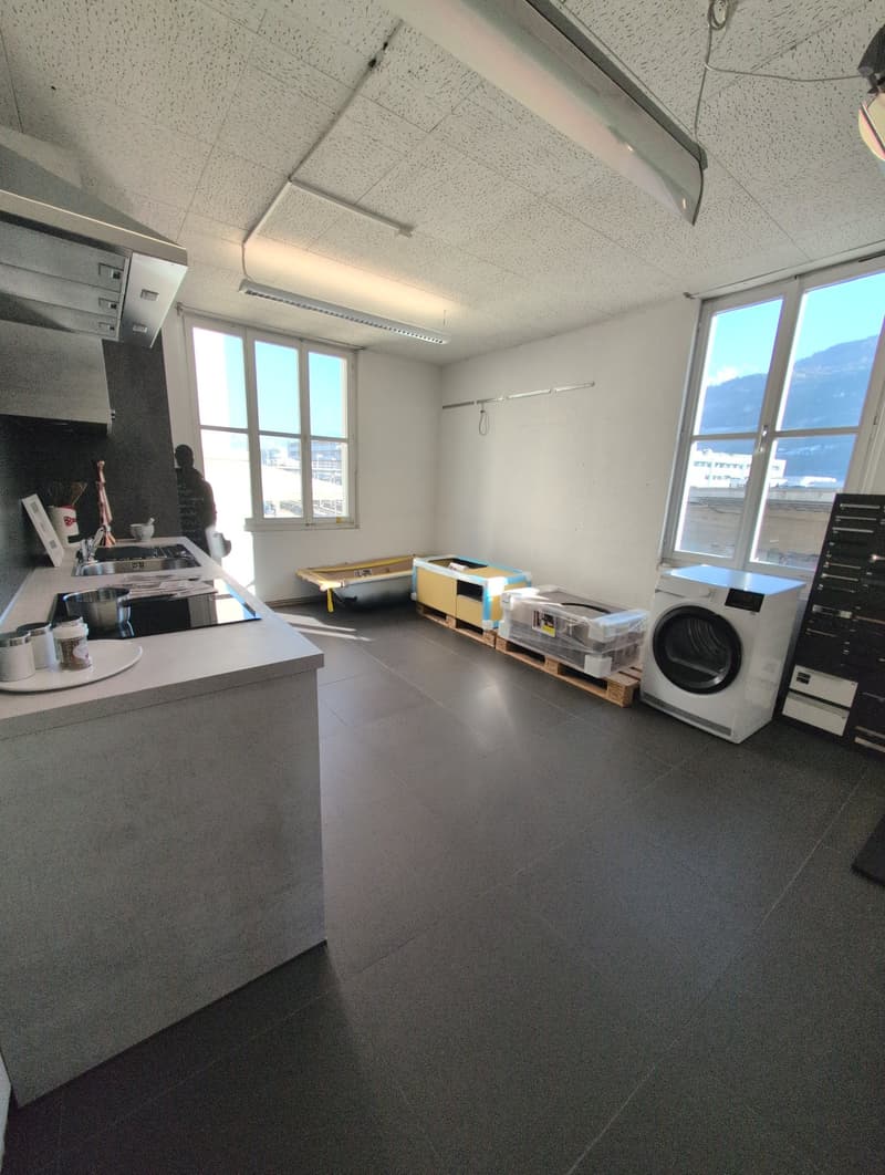 Empty room, kitchen area with sink and range hood, washing machine, storage boxes, large windows