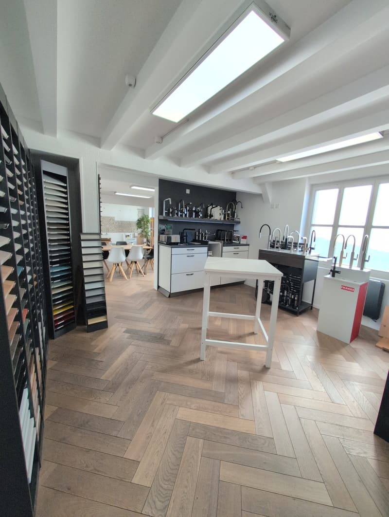Wooden herringbone floor, white cabinets, white countertop, faucets, lights, kitchen equipment, tables, chairs