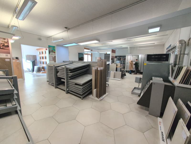 interior of a showroom, hexagon floor tiles, fluorescent ceiling lights, stacks of materials, shelving units