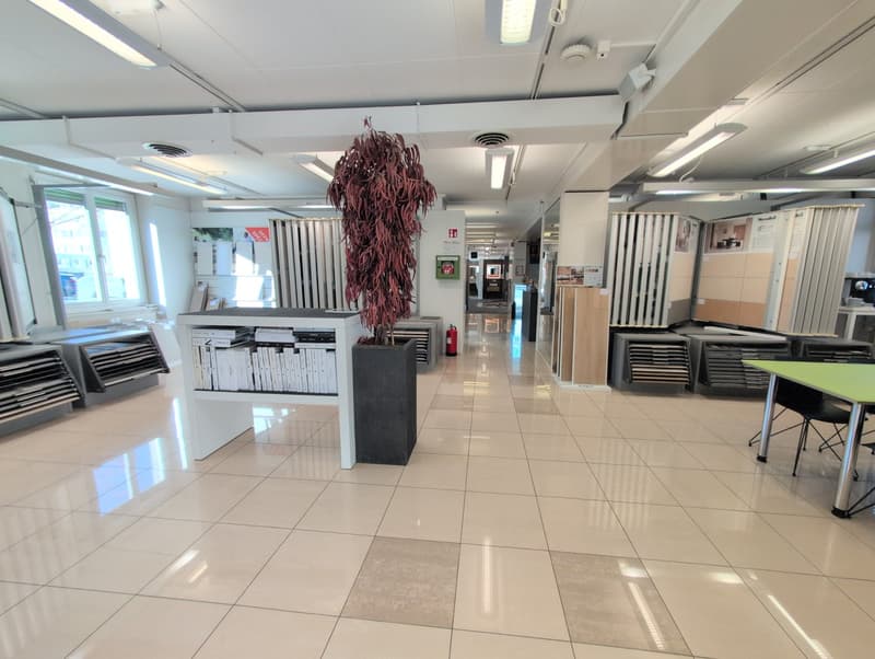 tiled floor, white ceiling, metal stands with books, a tall plant, glass windows, a fire extinguisher, tables and chairs