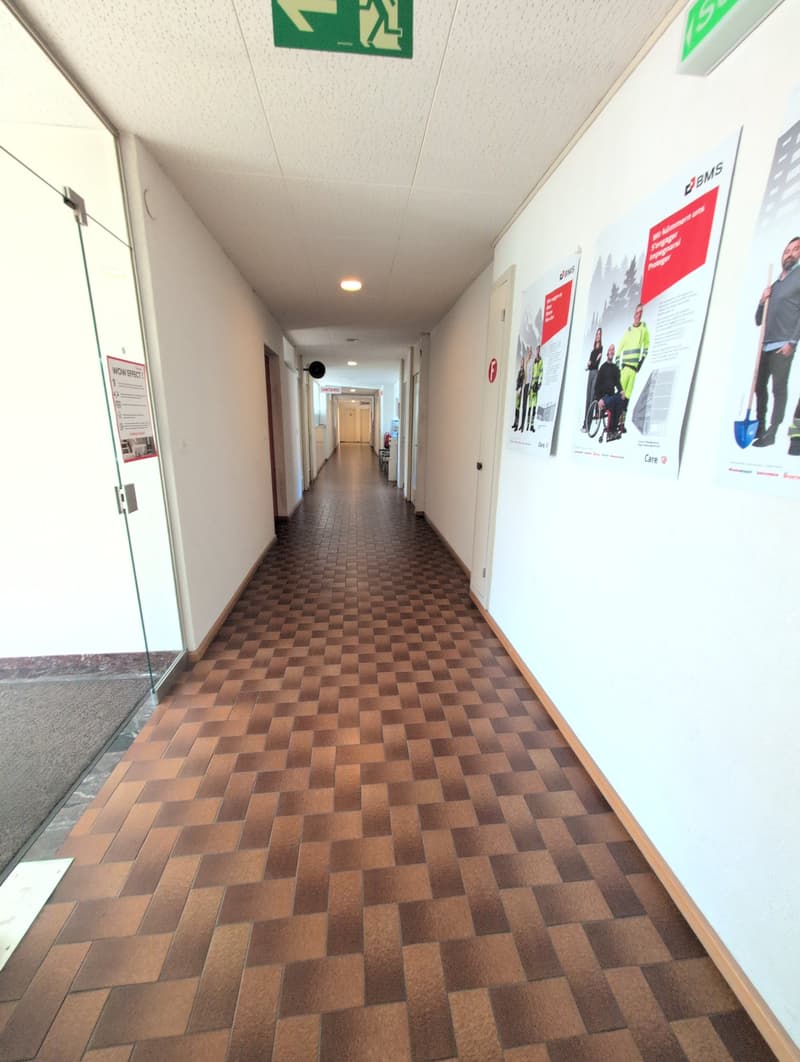 wide hallway, brown checkered flooring, white walls, glass door, posters