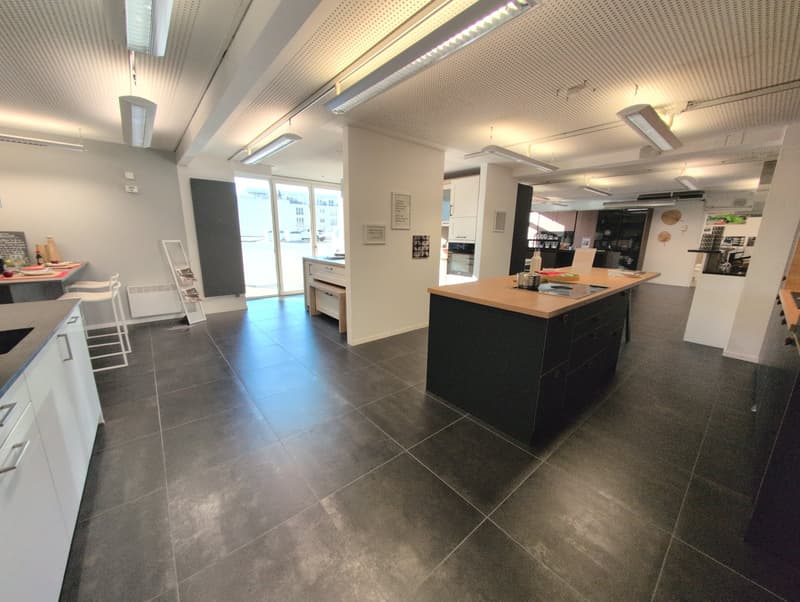Modern kitchen with open floor plan, black tiles, white cabinetry, glass doors, large kitchen island, contemporary lighting