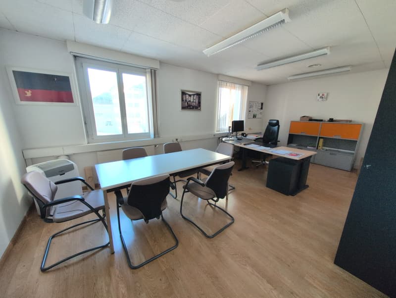 empty room with desk and chairs, window with blinds, office shelves with books and folders, air conditioner, meeting table, computer monitor, lamps on ceiling