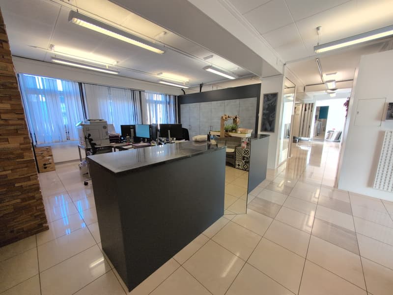 modern office with tiled floor, a large reception desk, monitors, printer, cabinets, and bright lighting