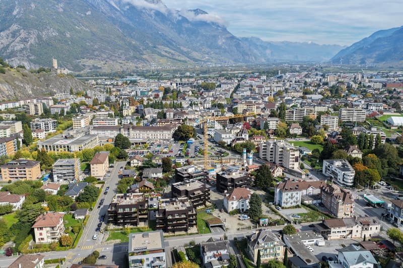 Aerial view of a town with many buildings, mountains in the background, and some in construction