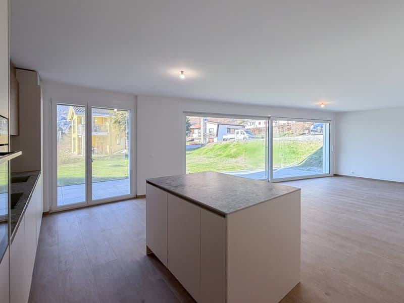 an open kitchen-living room with hardwood flooring, kitchen cabinets, and sliding glass doors leading to a terrace overlooking a grassy slope