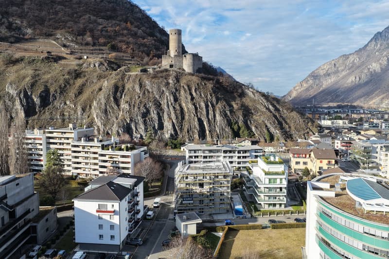 Residential buildings with some in construction, mountainous area with a castle, clear sky