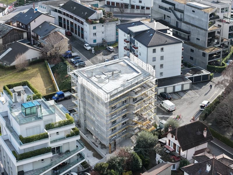 Aerial view of a residential area with multiple buildings, including a building under construction with scaffolding.