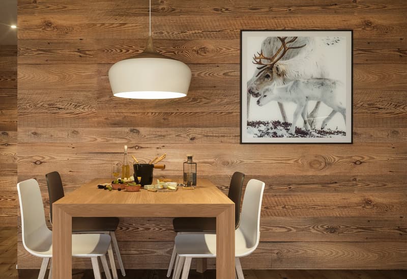 wooden table with 4 chairs, wooden wall, wooden floor, white pendant light, picture frame with reindeer image