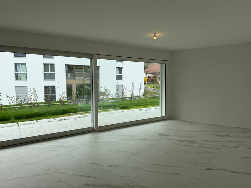 empty room, large sliding glass doors, white tiled floor, white walls, view of a grassy area