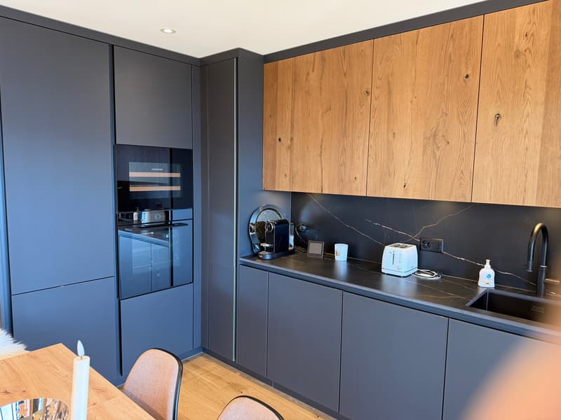 modern kitchen with wooden cabinets, black countertops, built-in oven, sink, toaster, and faucet