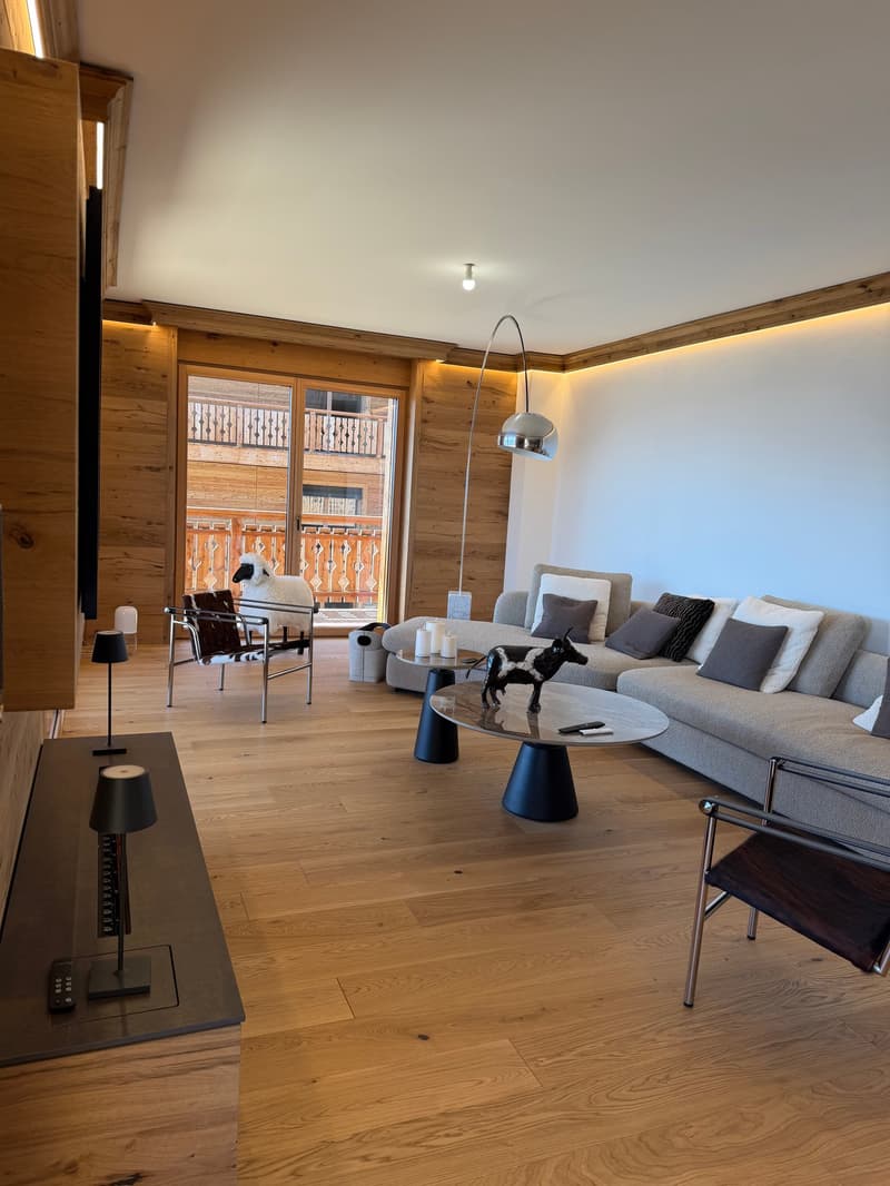 wooden floor, large windows, sofa, coffee table, lamps, TV, remote control, sheep statue, cow statue