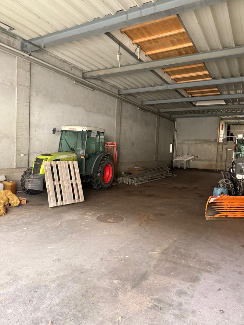 Empty garage with a tractor, wooden pallet, and other items