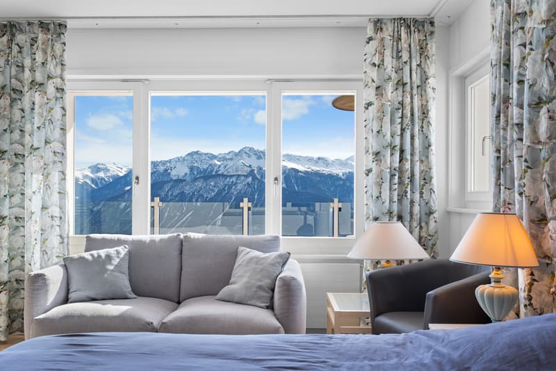 une chambre avec une grande fenêtre donnant sur les montagnes et un lit / a bedroom with a large window overlooking mountains and a bed