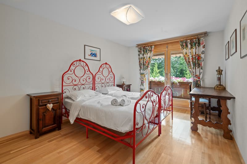 une chambre avec du parquet, une grande fenêtre et un lit blanc / a bedroom with wood floors, a large window, and a white bed