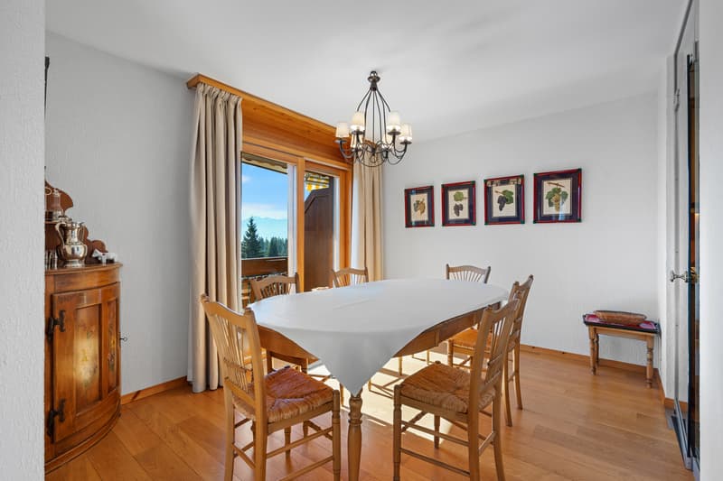 / a room in a home with wooden floors, a large window, and a white table and chairs