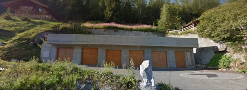 Subterranean garage building with a sloped roof and multiple garage doors.