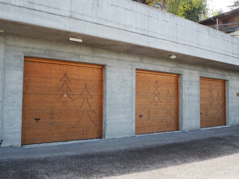 Building with three wooden garage doors with Christmas tree carvings