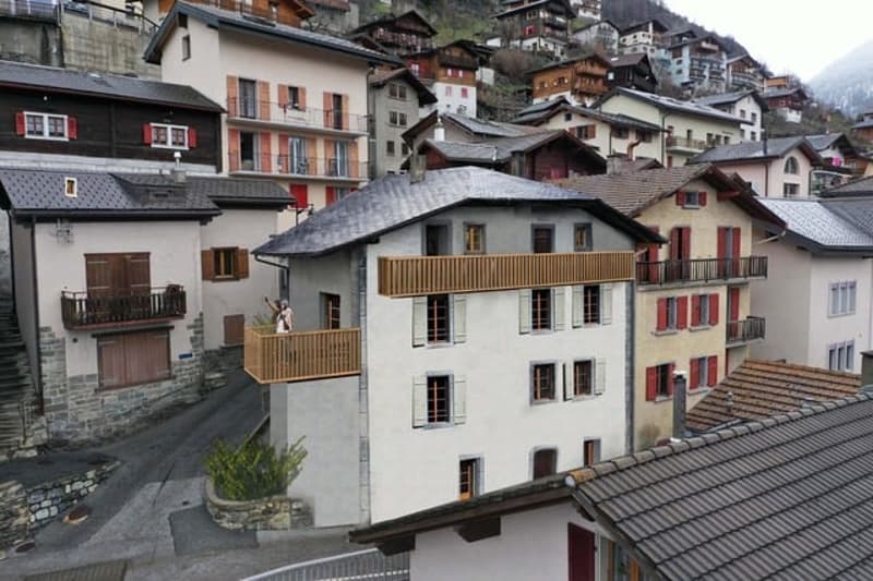 3 story house, balcony, gray roofs, red shutters, cobblestone street, neighboring houses