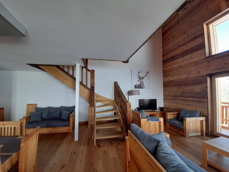 wooden floor, staircase, wood wall, gray sofa, blue pillows, glass table