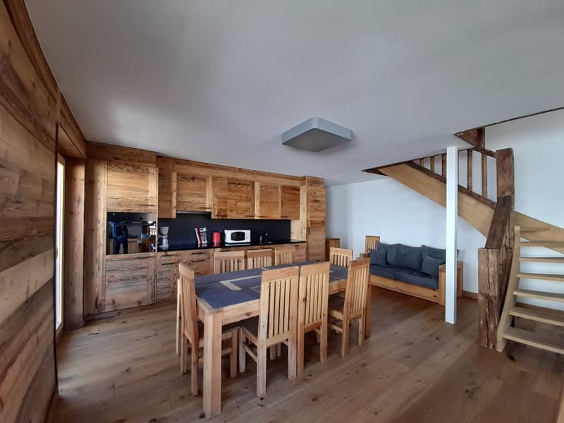open concept kitchen and living room, wooden floor, dining table, couch, wooden stairs, wooden cabinets