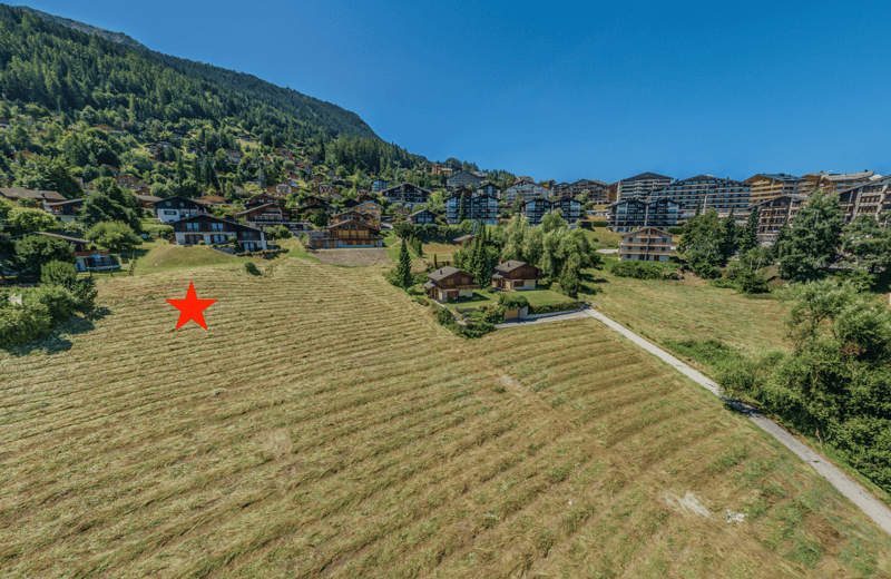 Aerial view of a town surrounded by mountains with a grassy field