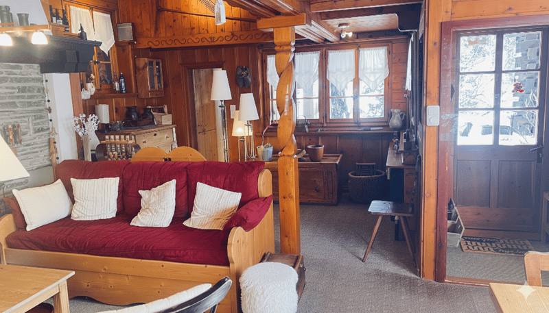 wooden walls, fireplace, red couch, wooden tables, wooden chairs, lamps, wooden pillar