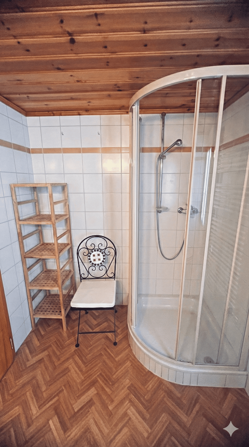 Bathroom with wooden floor, white tiled walls, shower, chair, shelf