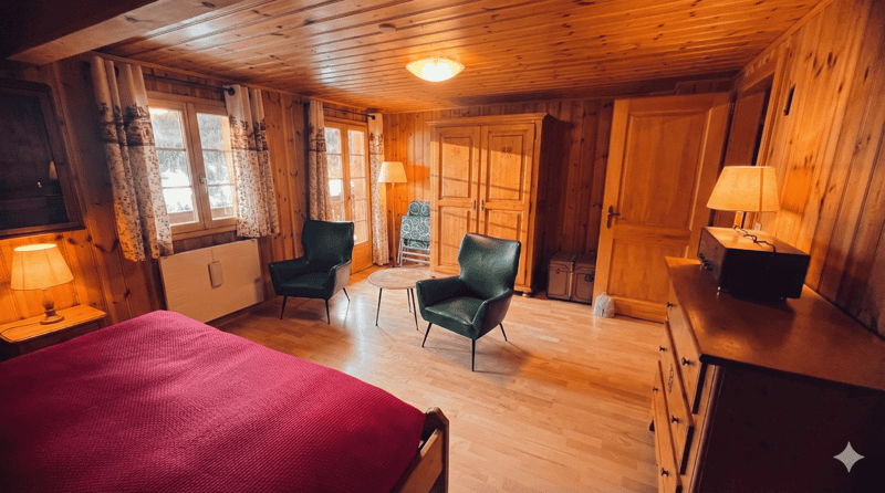 Bedroom with wooden walls, bed, chairs, lamps, table, wardrobe, radiator, windows with curtains