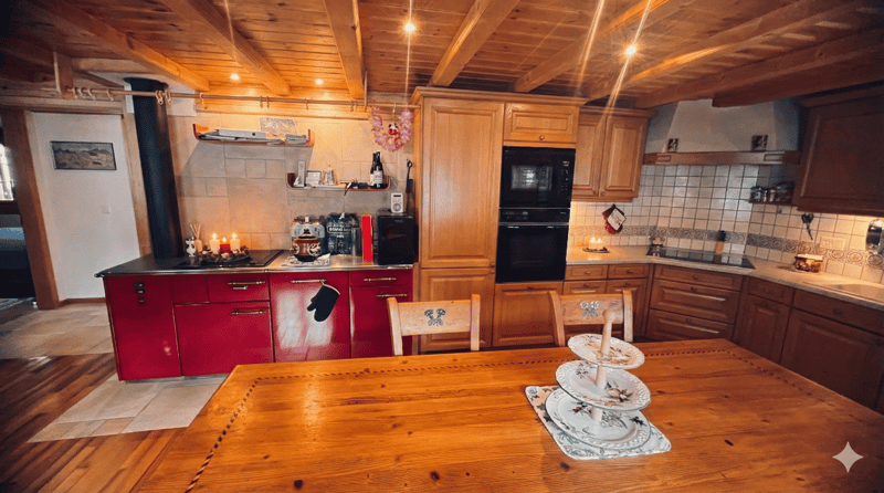 wooden ceiling, wooden floor, red kitchen cabinets, wooden dining table, microwave, oven, sink, plates, candles