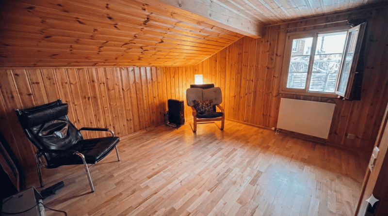 wooden walls, wooden floor, two chairs, radiator, window