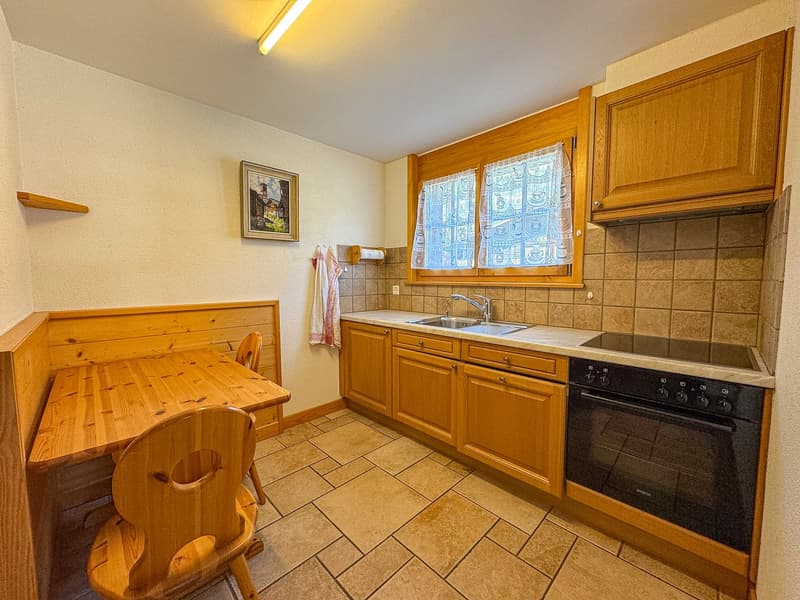 kitchen with wooden cabinets, tiled floor, wooden table, sink, oven, window with curtains