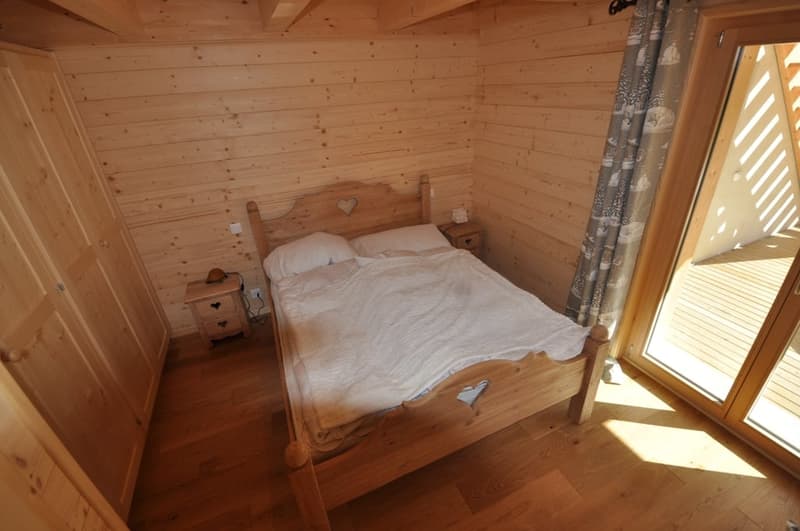 Cozy wooden bedroom with a large bed, wooden furniture, and a window with a view of the outdoors.