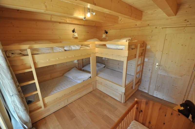 Wooden cabin-style bedroom with bunk beds, wooden walls and ceiling, and wooden flooring.