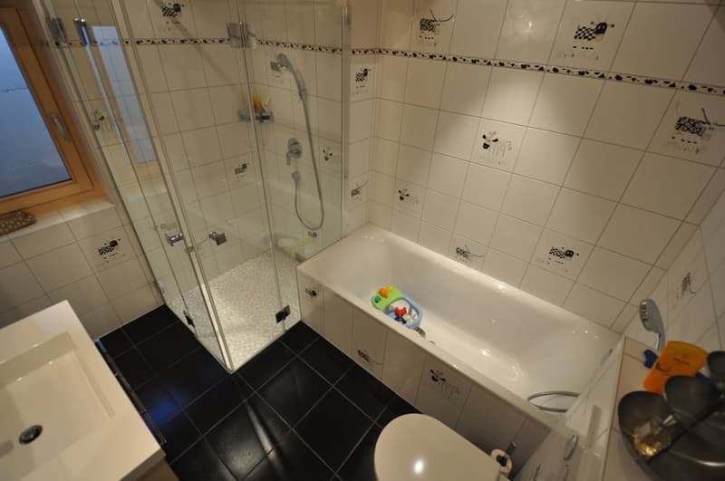 Tiled bathroom with a bathtub, shower, and various bathroom accessories